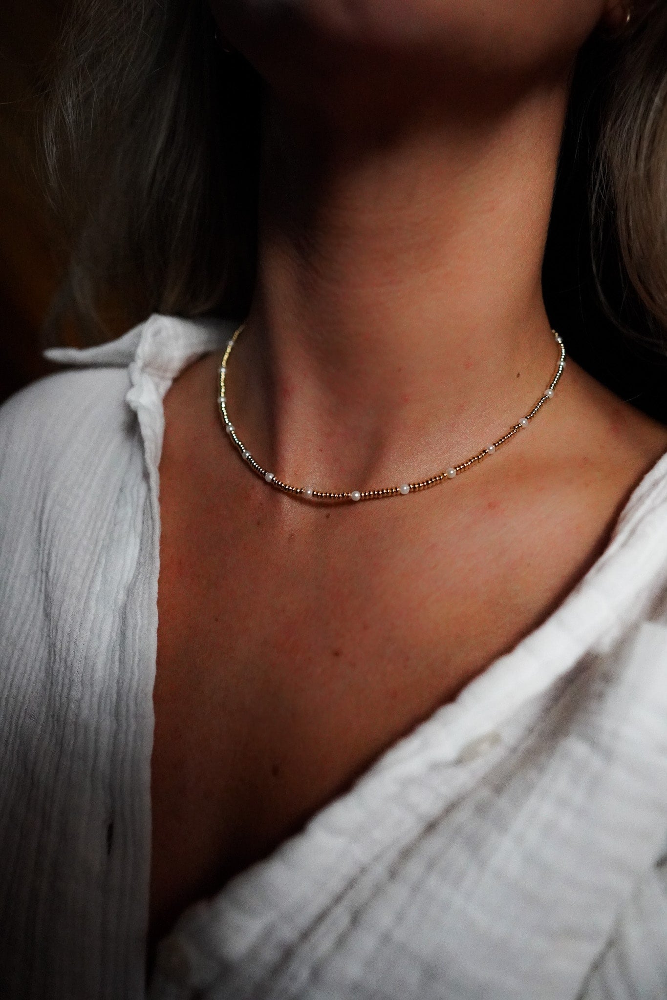 INDIVIJWL Gold and Pearl Beaded Choker Necklace shown on a model, featuring 24k gold-filled 3mm spacer beads and delicate shell pearls. This 16-inch tarnish-resistant choker is designed to enhance natural beauty and symbolize emotional balance.