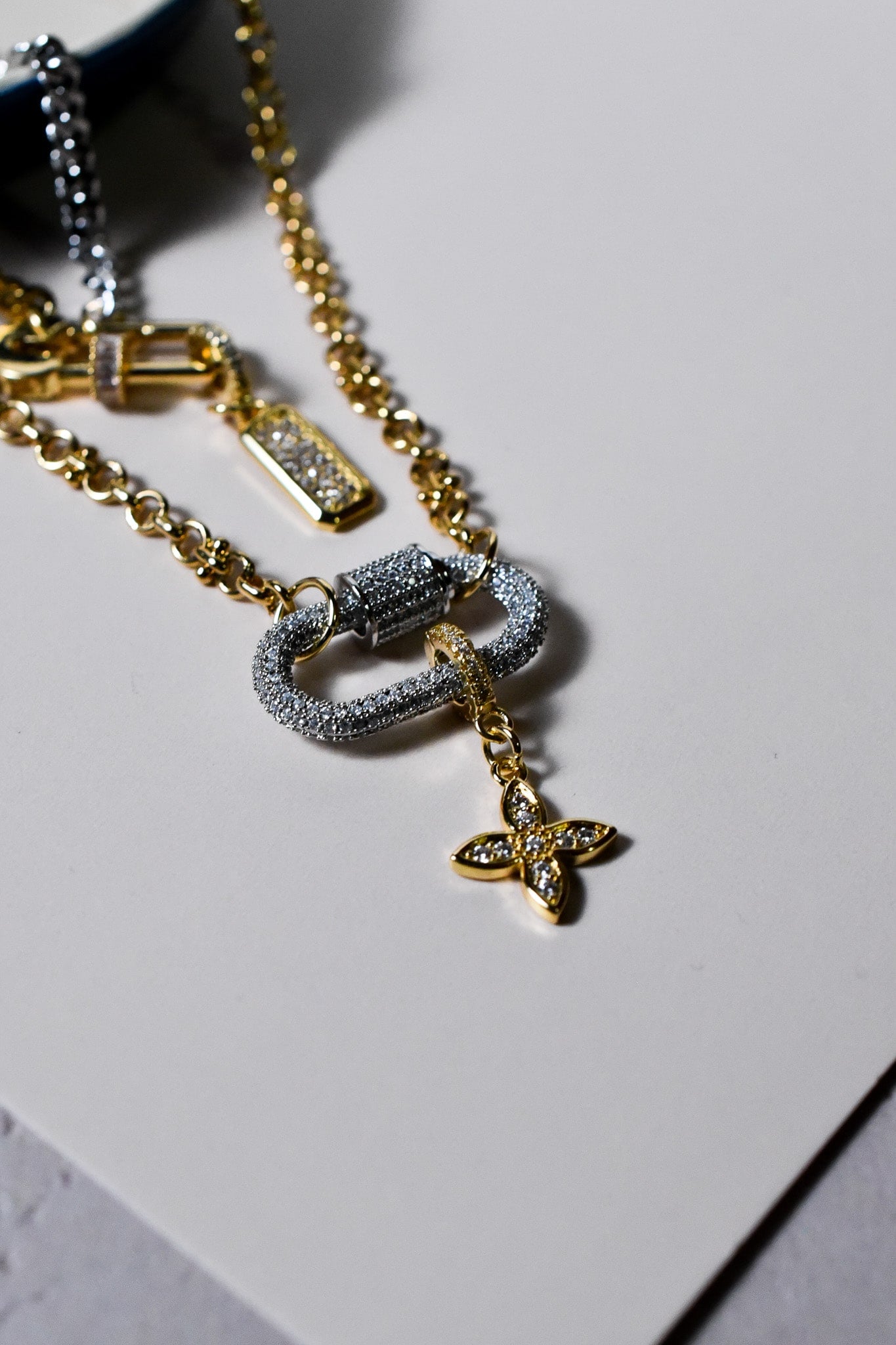 INDIVIJWL Peacemaker necklace close-up, highlighting the mixed metal design with a gold plated CZ safety pin lock, silver carabiner lock, and double rolo chain. Includes a 24k gold filled medium CZ pendant and detachable charm holder.