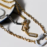 Detailed view of the INDIVIJWL Peacemaker necklace, showcasing a 24k gold plated CZ safety pin lock, silver carabiner, and 24k gold filled chains. A bold, customizable piece with a medium CZ pendant and removable charm holder.