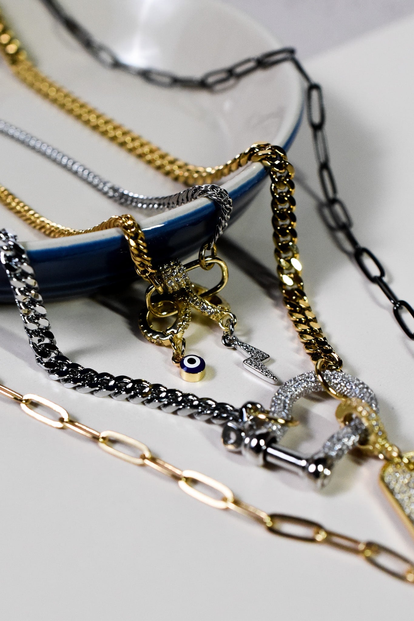 INDIVIJWL jewelry styled with multiple gold and silver chains, showcasing the blue evil eye charm with a cubic zirconia gold-filled removable bail. An elegant, protective accessory for layering necklaces.