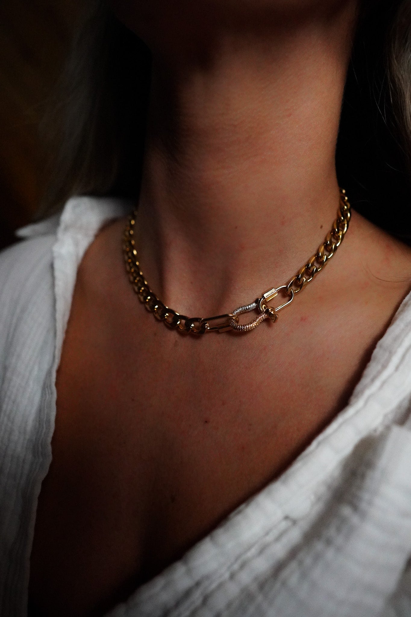 INDIVIJWL Gold Chunky Cuban Chain shown on a model featuring a 24k gold-filled 9.6mm Miami Cuban curb chain with two mini gold carabiner locks and a 14k gold-filled large carabiner closure with micro paved CZ. This 16-inch statement necklace adds bold elegance to any look.