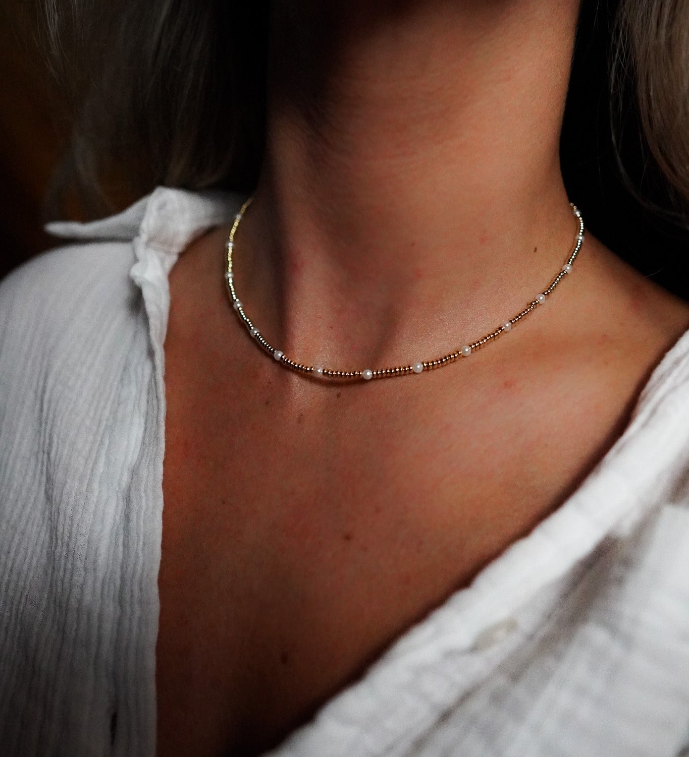 INDIVIJWL Gold and Pearl Beaded Choker Necklace shown on a model, featuring 24k gold-filled 3mm spacer beads and delicate shell pearls. This 16-inch tarnish-resistant choker is designed to enhance natural beauty and symbolize emotional balance.